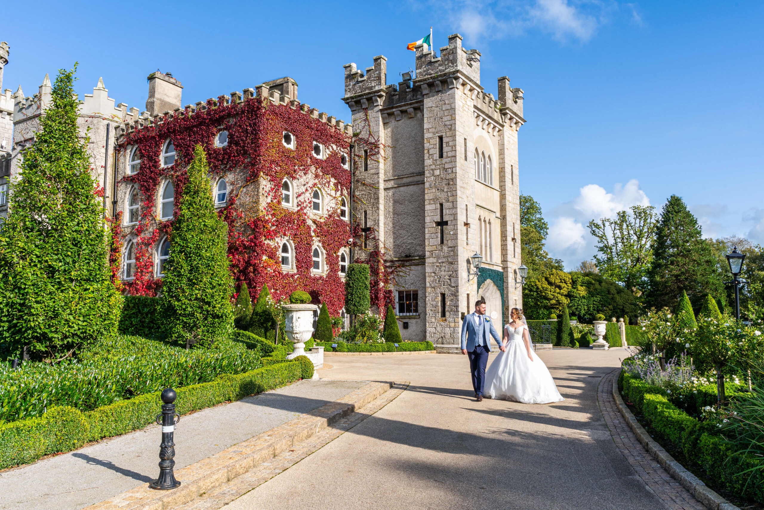 Bride and groom walking by Cabra Castle on sunny day