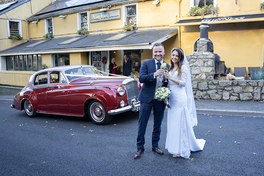 Bride and groom outside The Angler's Rest with wedding car